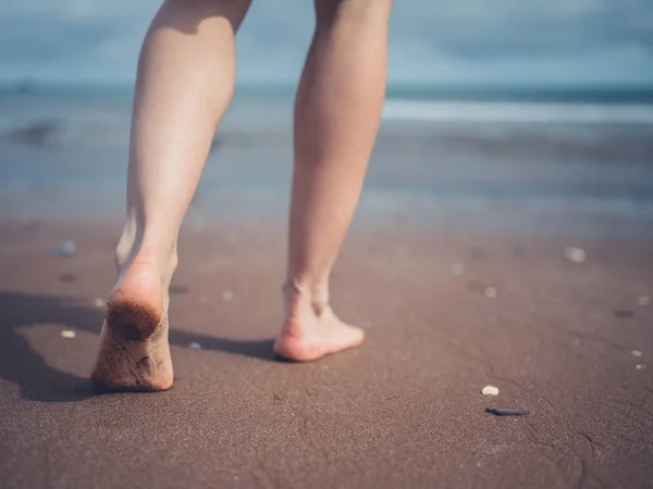 Młoda kobieta spacerująca po plaży — Zdjęcie stockowe