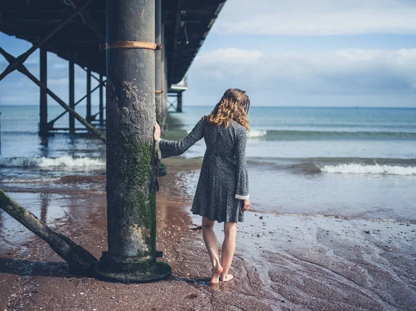 Giovane donna in piedi sotto il molo — Foto Stock
