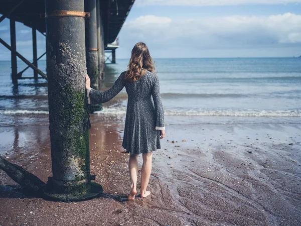 Junge Frau steht unter Seebrücke — Stockfoto