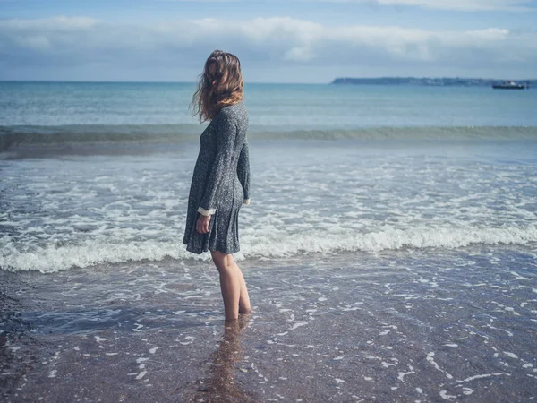 Ung kvinna som står på stranden — Stockfoto