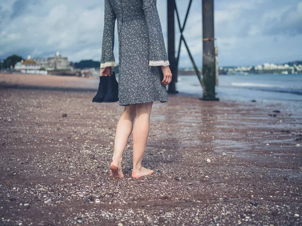 Женщина, идущая по пляжу с обувью в руке — стоковое фото