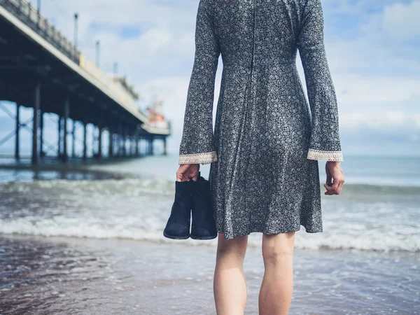 Mujer caminando en la playa con zapatos en la mano — Foto de Stock