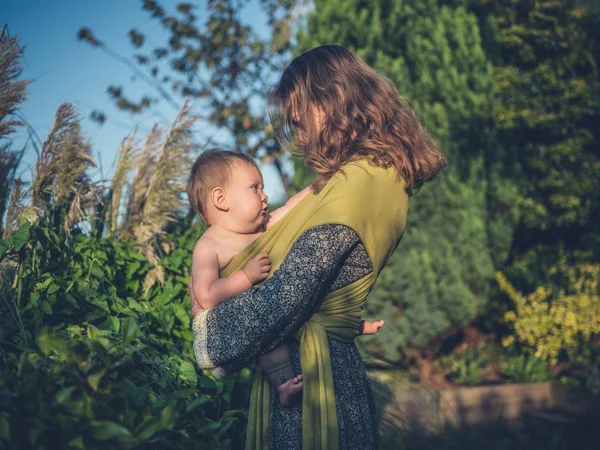 Mãe com bebê no jardim ao pôr do sol — Fotografia de Stock