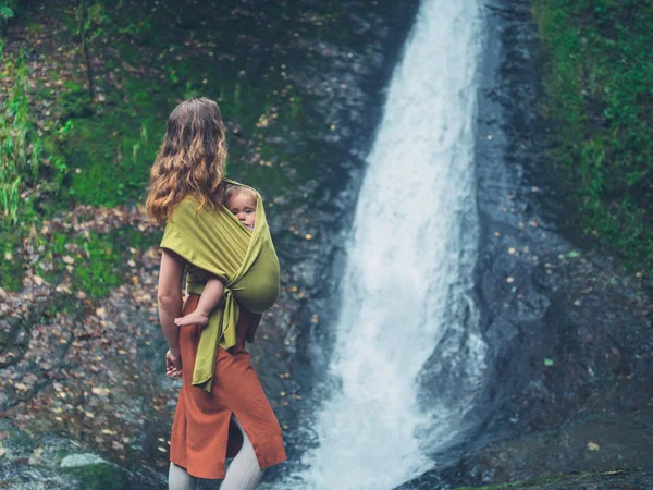 Madre con el bebé de pie junto a la cascada —  Fotos de Stock