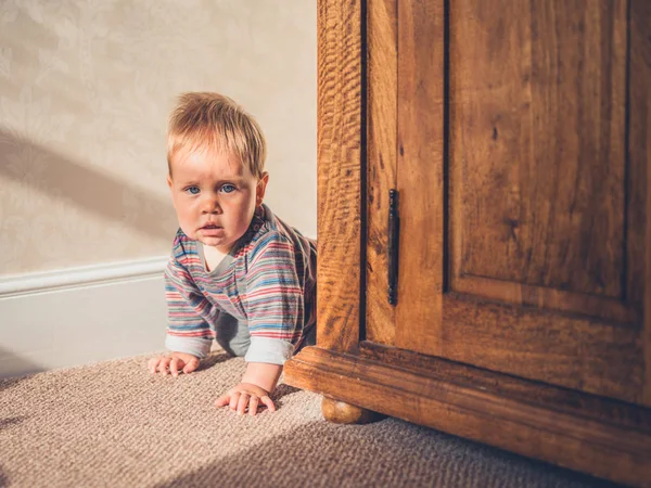 Little baby hiding behind wardrobe — Stock Photo, Image