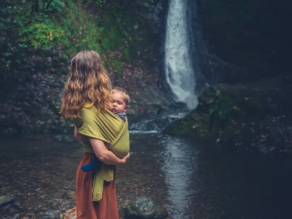 Мать с ребенком стоит у водопада — стоковое фото