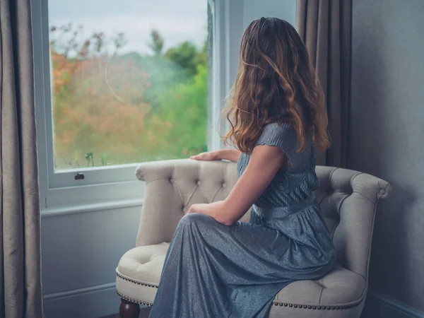 Jonge vrouw dagdromen door raam — Stockfoto