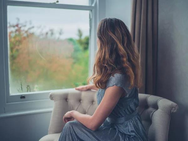 Jonge vrouw dagdromen door raam — Stockfoto
