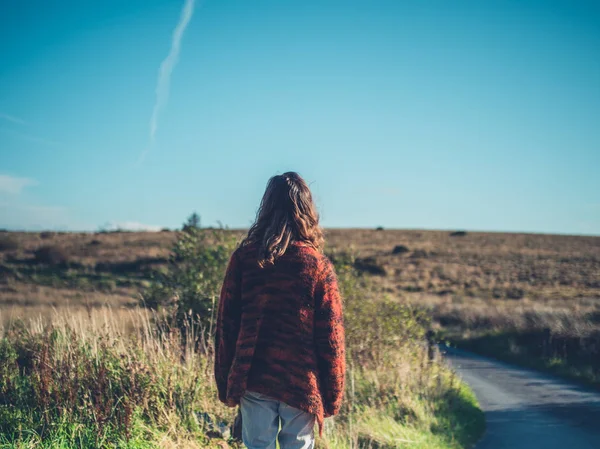 Vrouw lopen op weg in de wildernis — Stockfoto