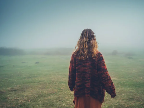 Giovane donna che cammina nella nebbia sulla brughiera — Foto Stock