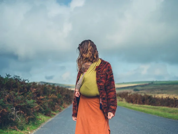 Vrouw met baby in draagdoek op weg in het land — Stockfoto