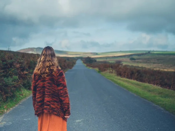 Jeune femme debout sur la route sur la lande — Photo