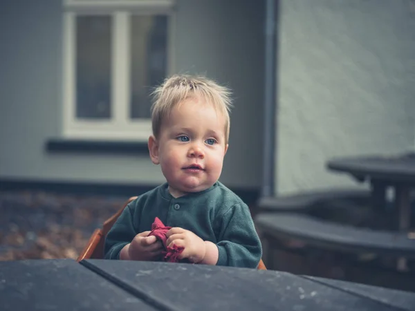 Baby sitting at table outside in autumn — Stock Photo, Image