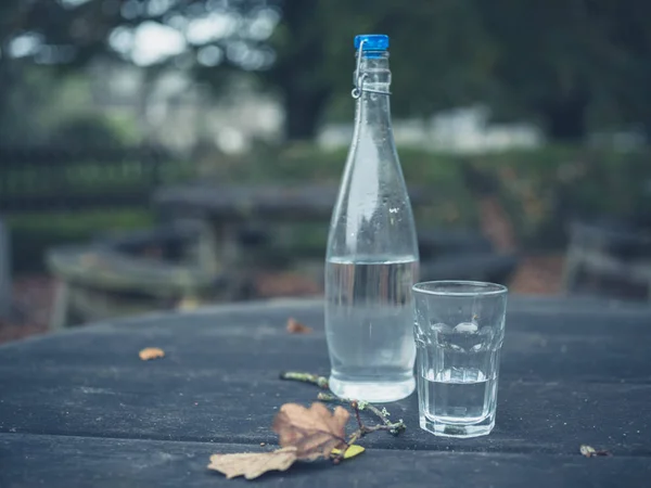 Water bottle and glass in autumn — Stock Photo, Image