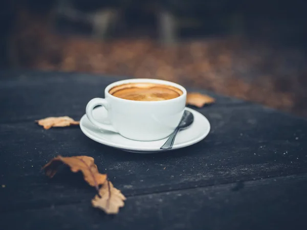 Kopje koffie op tafel met bladeren in de herfst — Stockfoto
