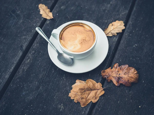 Cup of coffee on table with leaves in autumn — Stock Photo, Image