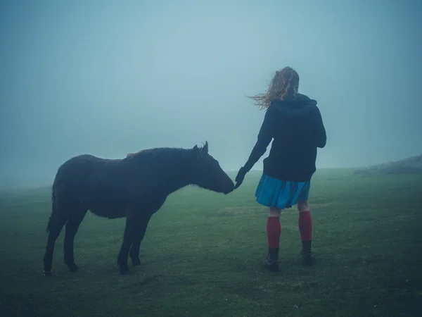 Vrouw een wilde pony aaien — Stockfoto
