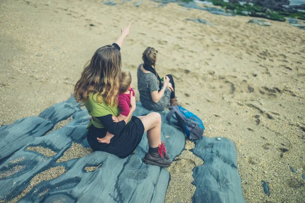 Dos mujeres con un bebé sentado en la playa — Foto de Stock