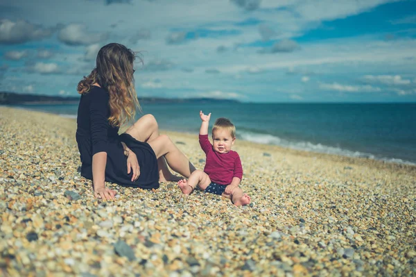 Молодая мать сидит на пляже со своим ребенком — стоковое фото