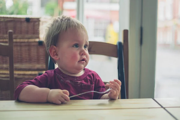 Маленький ребенок сидит за столом в кафе — стоковое фото