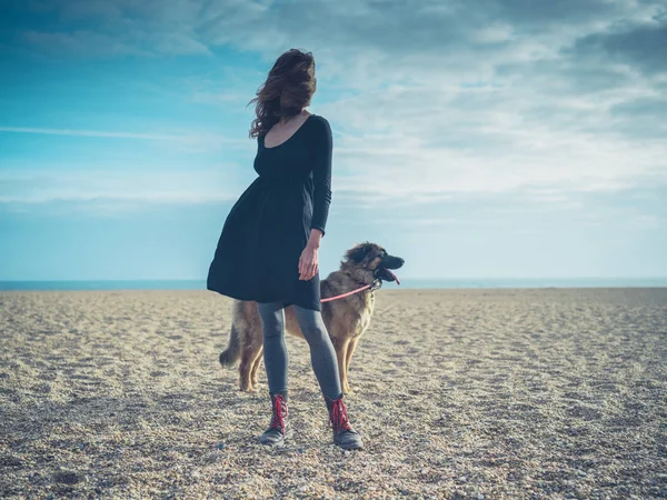Jonge vrouw op strand met gigantische hond — Stockfoto