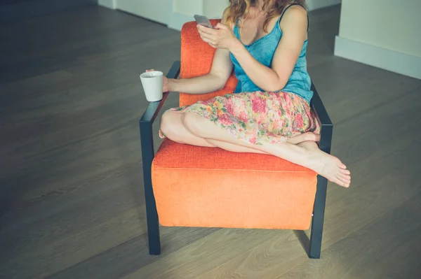 Giovane donna con tazza e smart phone a casa — Foto Stock