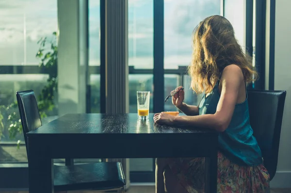 Mujer joven desayunando junto a la ventana de la ciudad — Foto de Stock