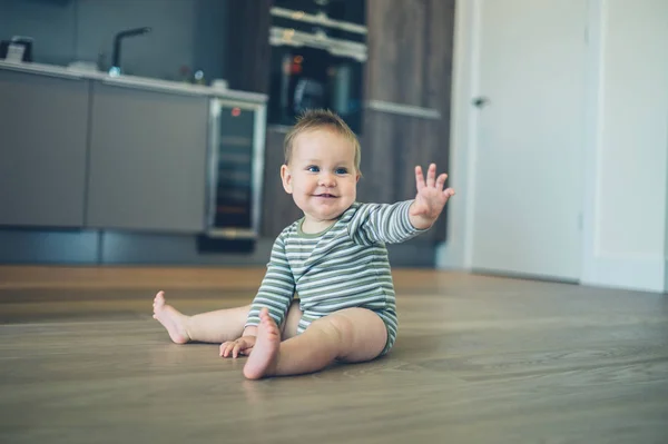 Pequeño bebé en el piso de la cocina saludando — Foto de Stock