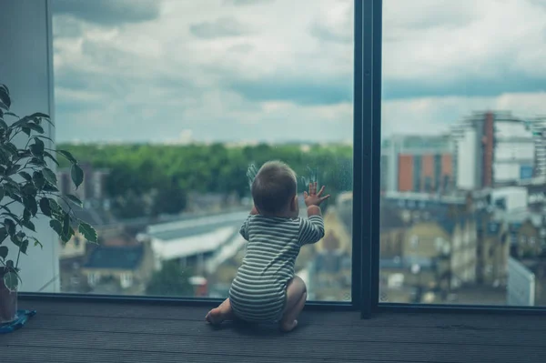 Маленький ребенок сидит на балконе в городе — стоковое фото