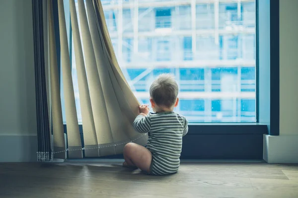 Kleine baby spelen met gordijn in appartement — Stockfoto