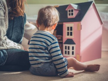Bir anne ve oğlu bir bebek evi ile oynuyorlar