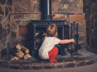 A little boy is playing with the log burner clipart