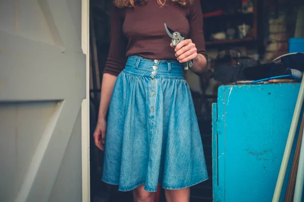 一个年轻女子站在整枝剪刀一般的棚子里 — 图库照片