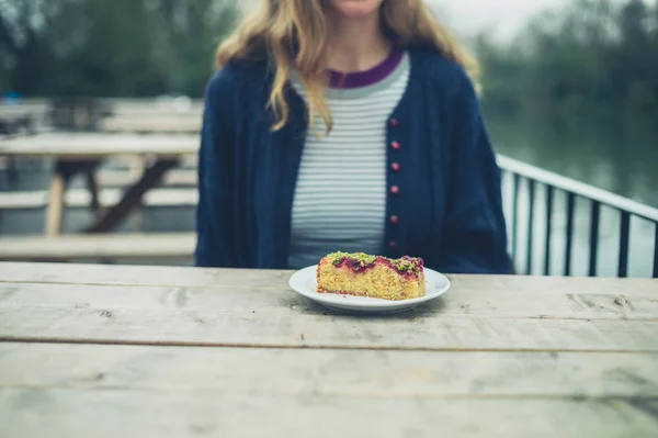 Μια Νεαρή Γυναίκα Κάθεται Ένα Τραπέζι Έξω Ένα Κομμάτι Κέικ — Φωτογραφία Αρχείου