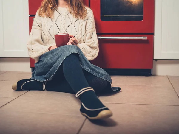 Μια Νεαρή Γυναίκα Κάθεται Στο Πάτωμα Της Κουζίνας Ένα Φλιτζάνι — Φωτογραφία Αρχείου