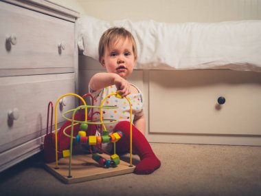 Küçük bir çocuk yatağının tarafından bir oyuncakla oynamak