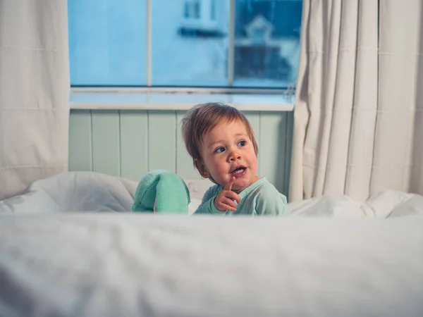 귀여운 아기는 부드러운 장난감 앉아서 가리키는 — 스톡 사진