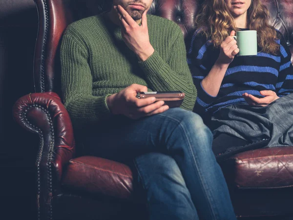 ホーム スマート フォンを使用し お茶を飲むでソファに座っている若いカップル — ストック写真