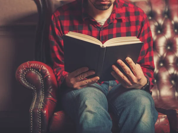 Joven Sentado Sofá Cuero Está Leyendo Libro —  Fotos de Stock