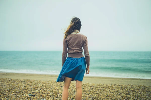Mujer joven de pie junto al mar en un día nublado — Foto de Stock