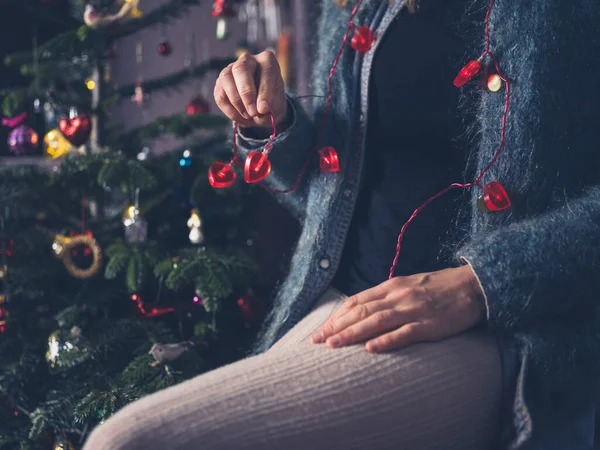 Genç Bir Kadın Noel Ağacının Yanında Oturuyor Elinde Kalp Şeklinde — Stok fotoğraf