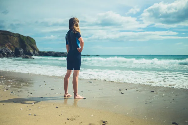 夏にはウェットスーツを着た若い女性が海岸に立っている — ストック写真