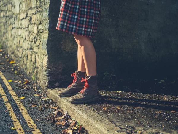 日落时站在路边的一位年轻女子的腿 — 图库照片