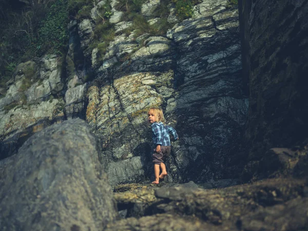 一个蹒跚学步的小孩在海边的岩石边走着 — 图库照片