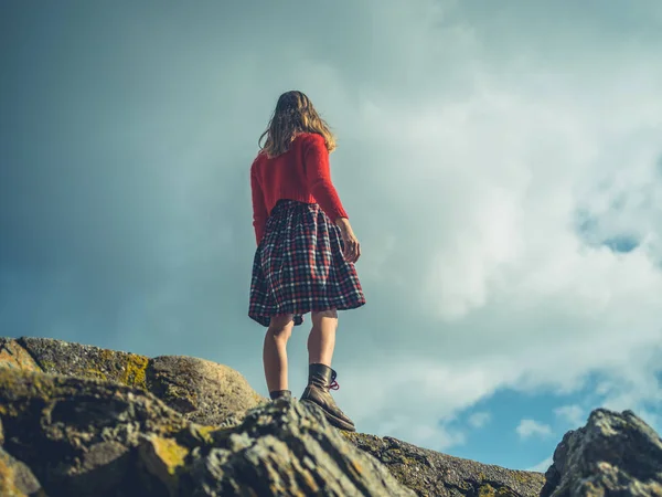 Genç Bir Kadın Mavi Gökyüzüne Karşı Bir Kayanın Üzerinde Duruyor — Stok fotoğraf