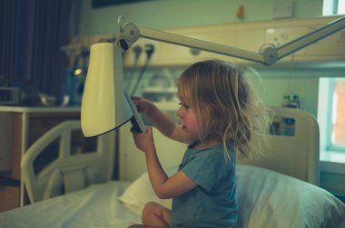 Küçük bebek elinde lambayla hastane yatağında