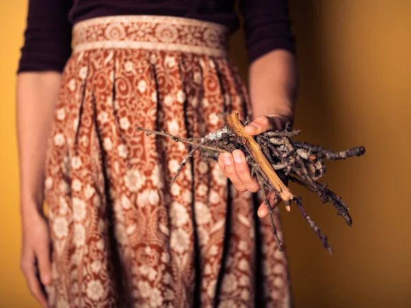 Junge Frau hält brennendes Holz in der Hand — Stockfoto