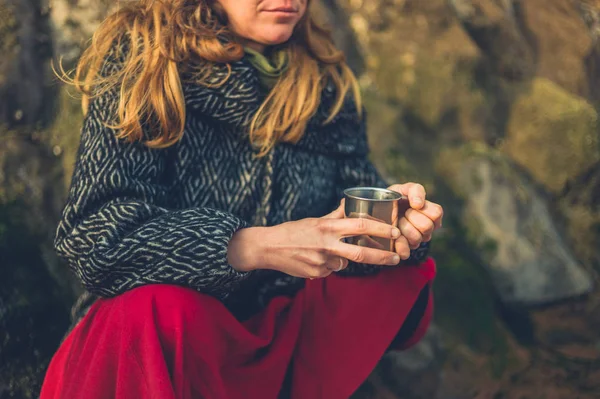 寒い女性が冬にビーチでお茶を飲んでいます — ストック写真