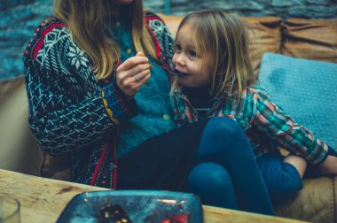 Mother feeding her toddler cake in a cafe
