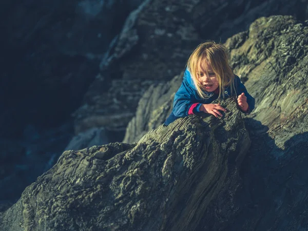 Little toddler climbing on rocks in winter — Stock Photo, Image